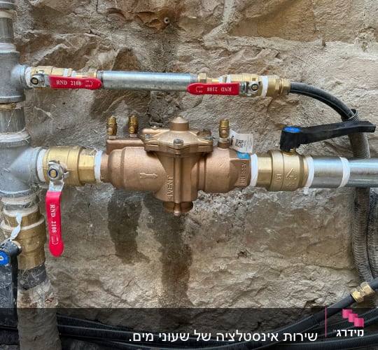 צנרת מתכת עם ברזים אדומים ושסתום פליז